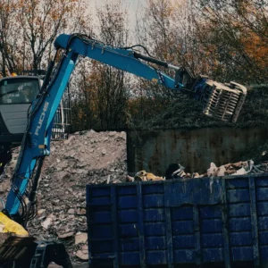 Close up of Skip Hire's mechanical grabber in action at Northwich, skilfully dumping waste into a larger container, illustrating efficient and precise waste handling.